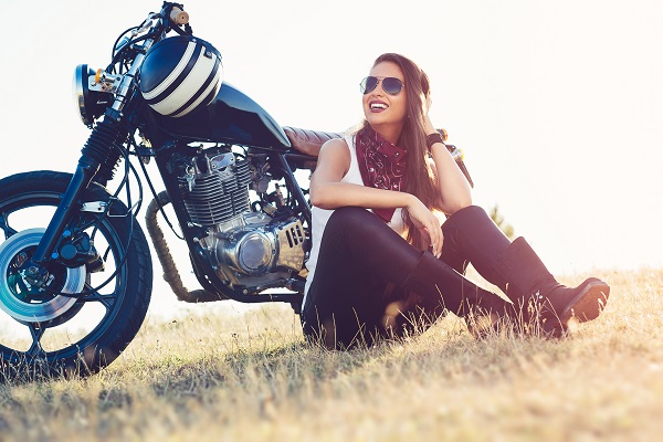 A woman sitting next to her motorcycle